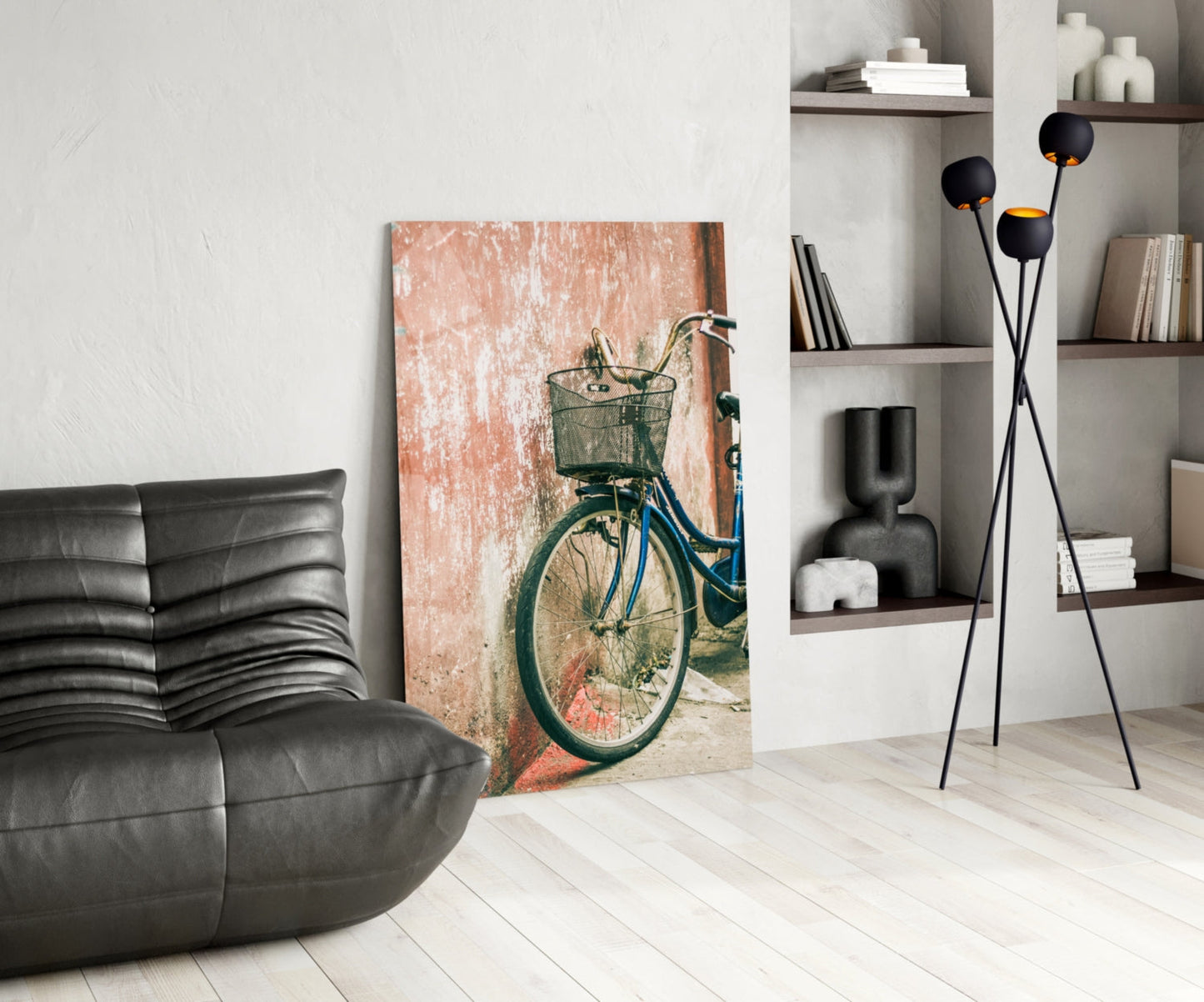Modern living room interior displaying vintage bicycle canvas leaning against wall beside black leather sofa and shelving unit.
