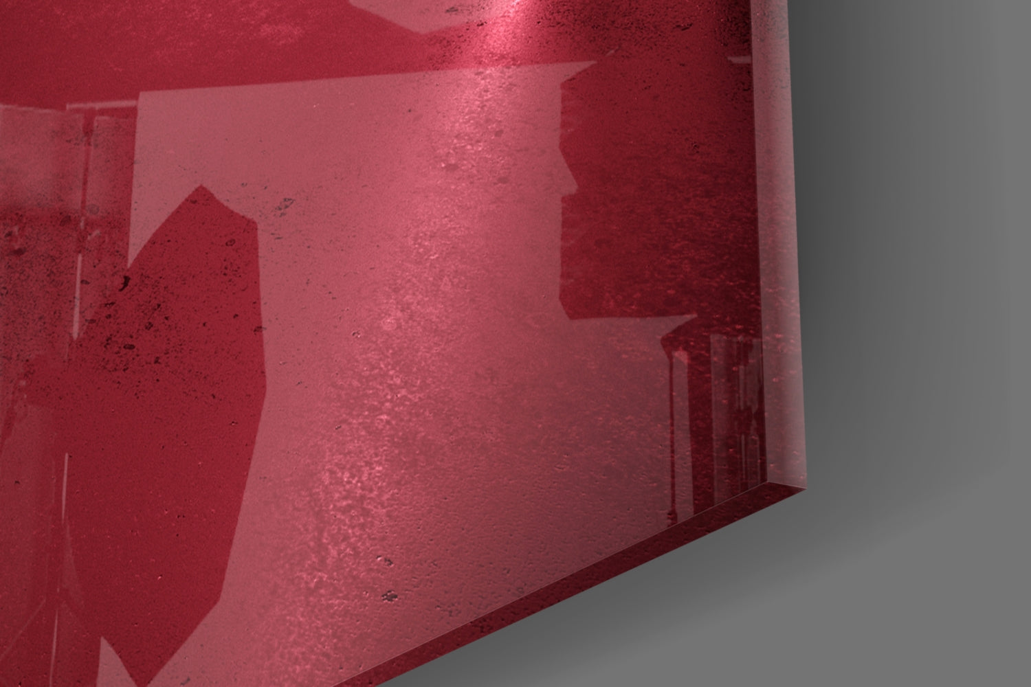 Angled view of deep pink glass wall art panel showing textured surface with subtle architectural silhouettes and weathered finish.