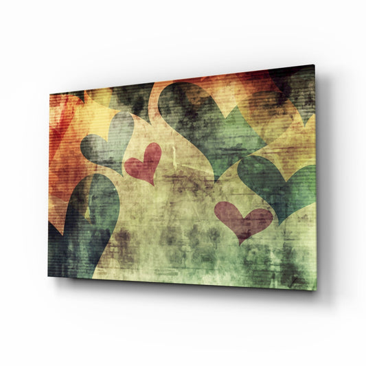 Angled view of glass wall art featuring overlapping hearts in red and dark tones on a grunge-textured background with warm yellow and green hues.