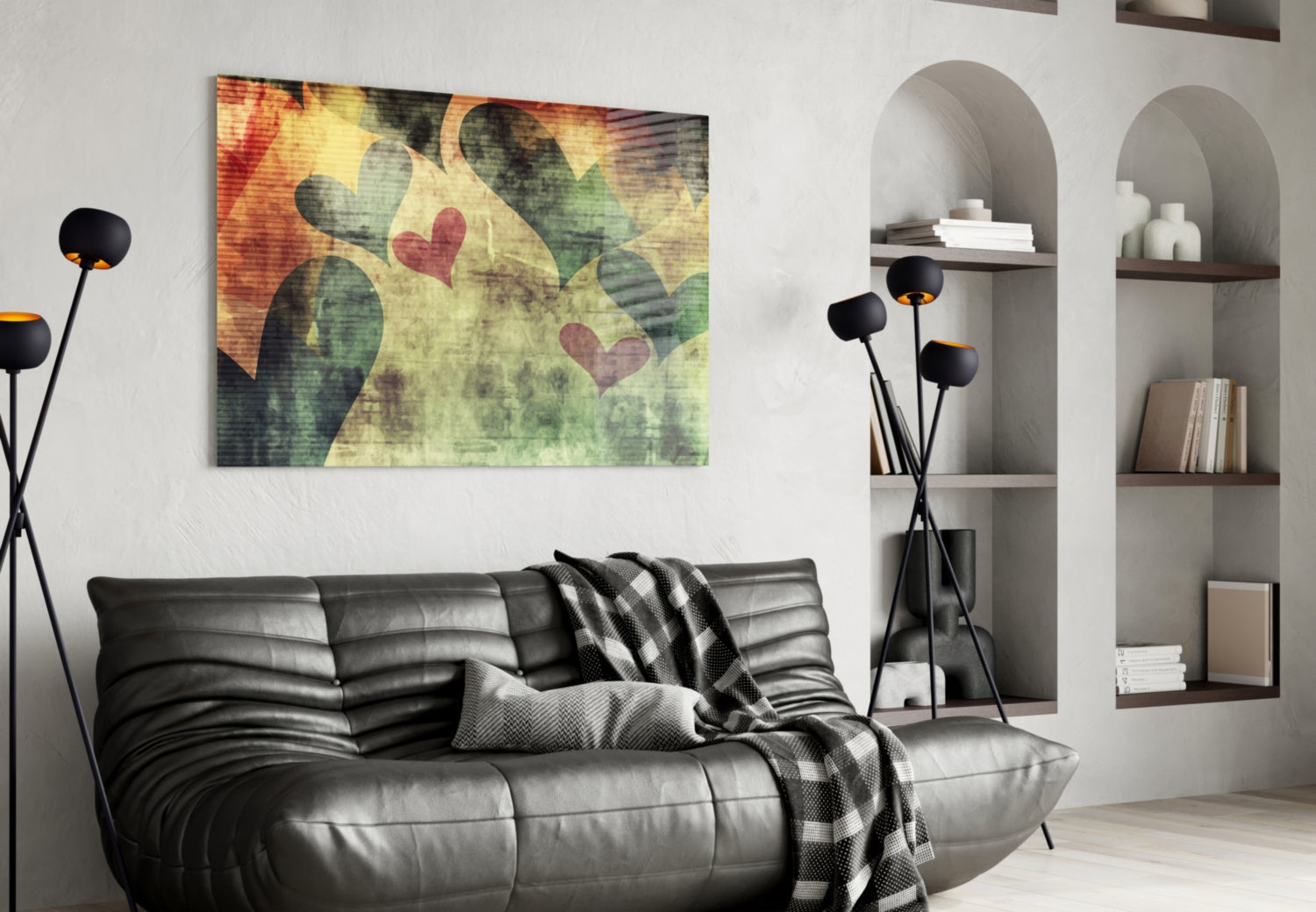 Glass wall art featuring cactus plants and red hearts in warm yellow and green tones, displayed above a black leather sofa in a modern living room.