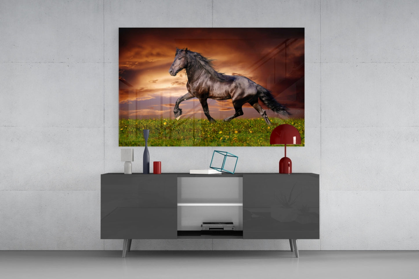 Black horse galloping across green field at sunset, displayed as framed glass art above gray media console.