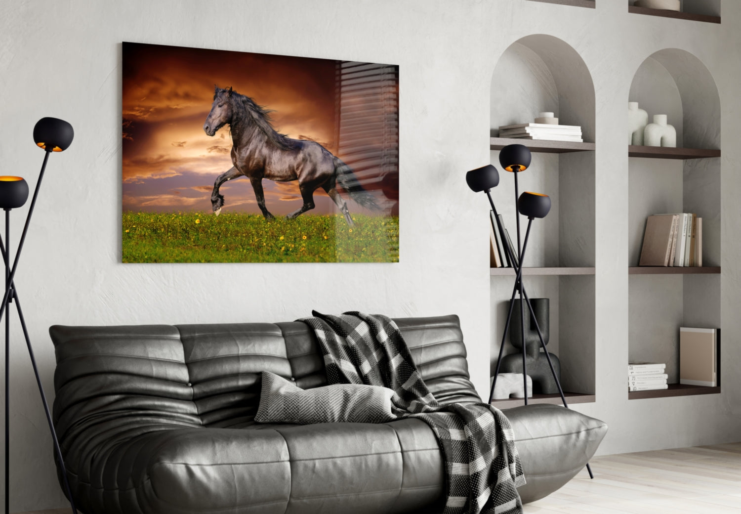 Glass wall art depicting a dark horse galloping across green meadow under golden sunset sky, displayed above gray leather sofa in modern living room.