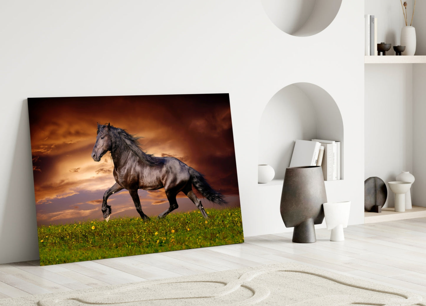 Black horse galloping across green field with dramatic orange sunset sky, leaning against white wall in minimalist room setting.