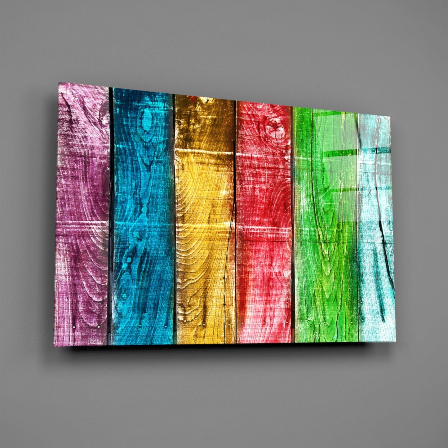 Angled perspective of colorful wood-textured glass wall art displaying six vertical panels in pink, blue, gold, red, green, and white.