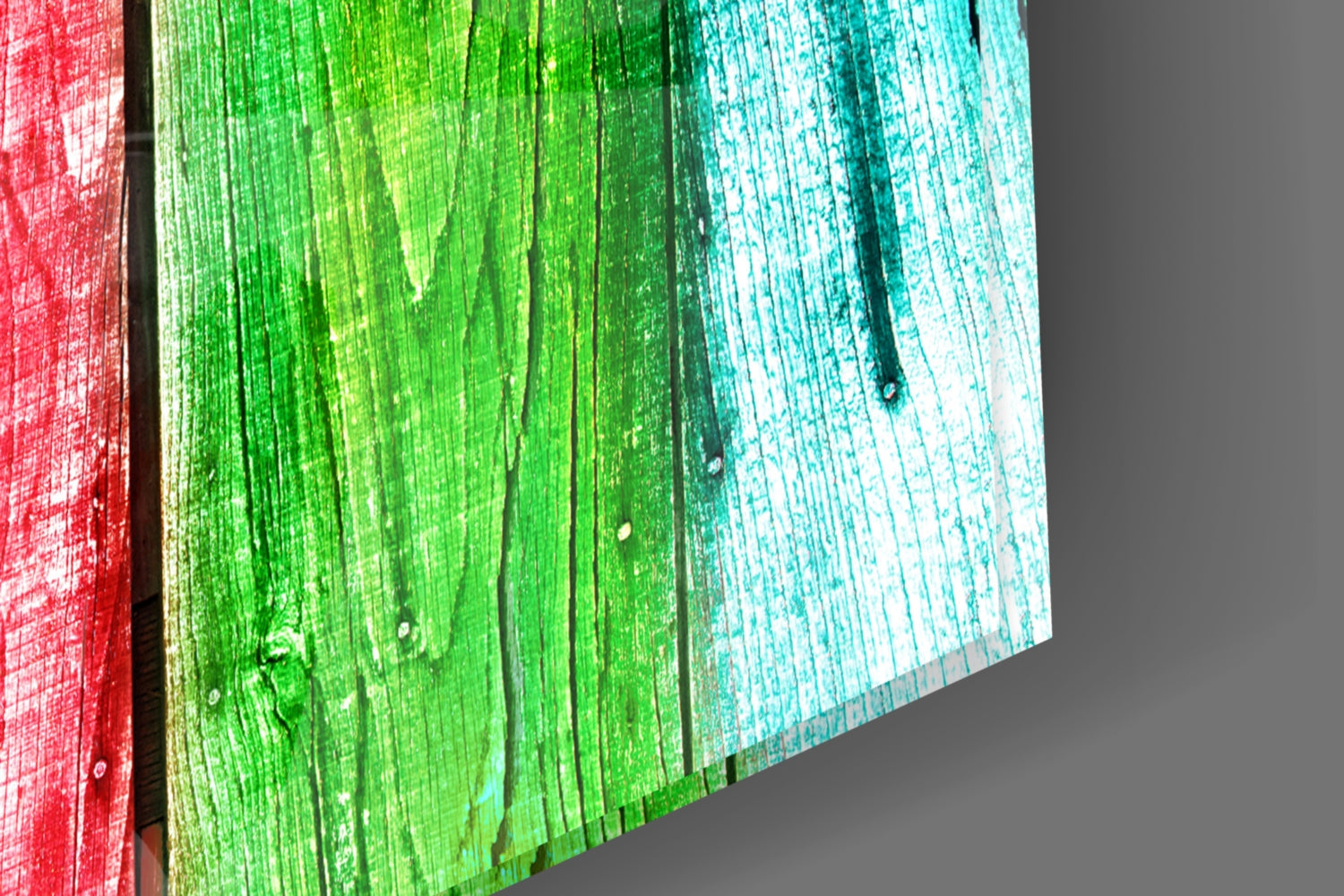 Close-up angled view of glass wall art with vertical wood grain texture in red, green, and turquoise color panels.