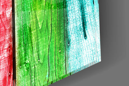 Close-up angled view of glass wall art with vertical wood grain texture in red, green, and turquoise color panels.