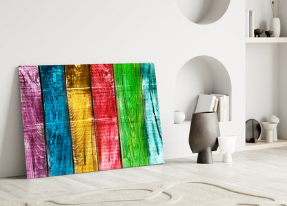 Colorful wood glass wall art leaning against white wall in minimalist interior with decorative objects.