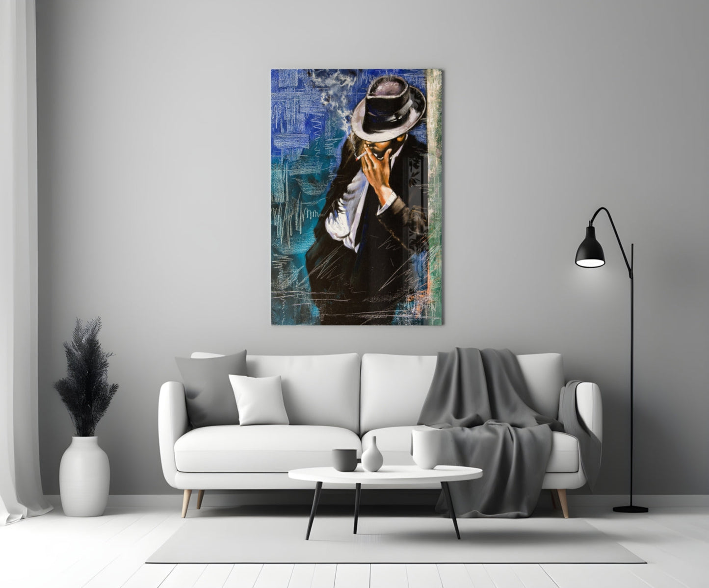 Framed glass wall art depicting a man in black suit and fedora hat against blue textured background, displayed above white sofa in modern living room.
