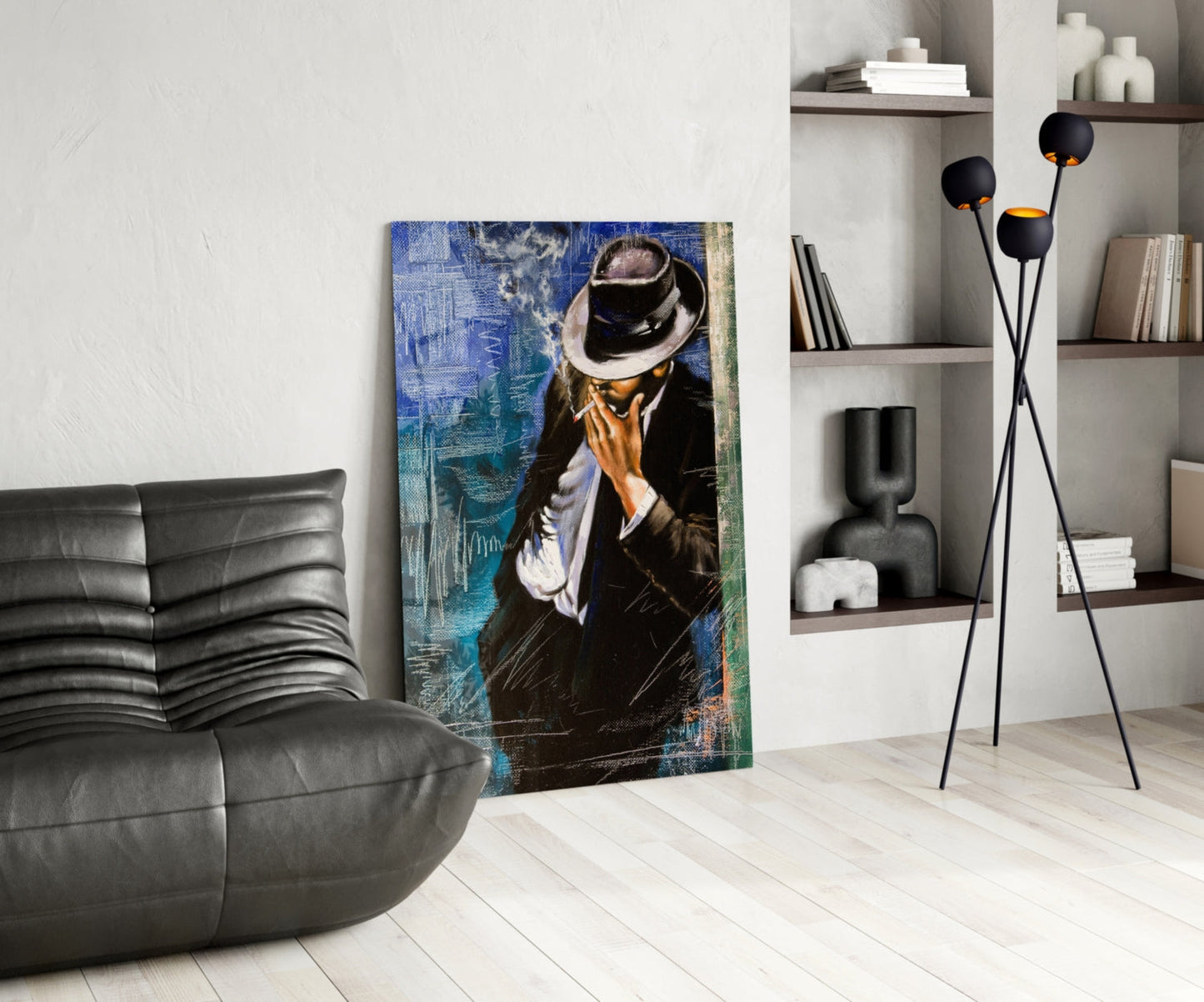 Modern living room with glass wall art depicting a man in black suit and fedora hat against blue textured background, displayed next to gray leather chair and black floor lamp.