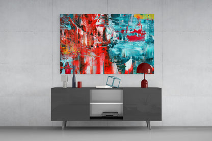 Modern living room with abstract glass wall art featuring red, turquoise, and yellow brushstrokes displayed above a dark sideboard.