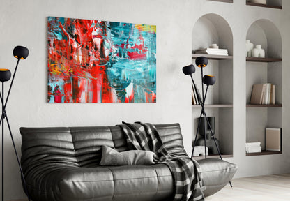 Modern living room with red and turquoise abstract glass art hanging above black leather sofa.