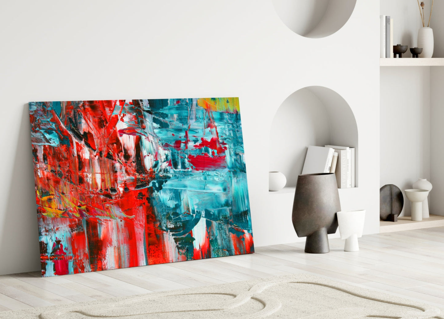 Vibrant abstract glass wall art featuring red and turquoise brushstrokes leaning against white wall in minimalist room setting.