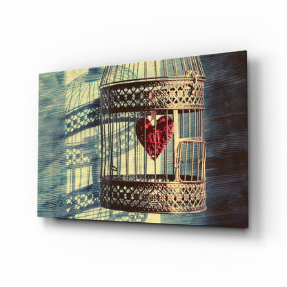 Ornate brass birdcage with red heart-shaped object inside, mounted on blue-stained wood with sunlight casting geometric shadows.