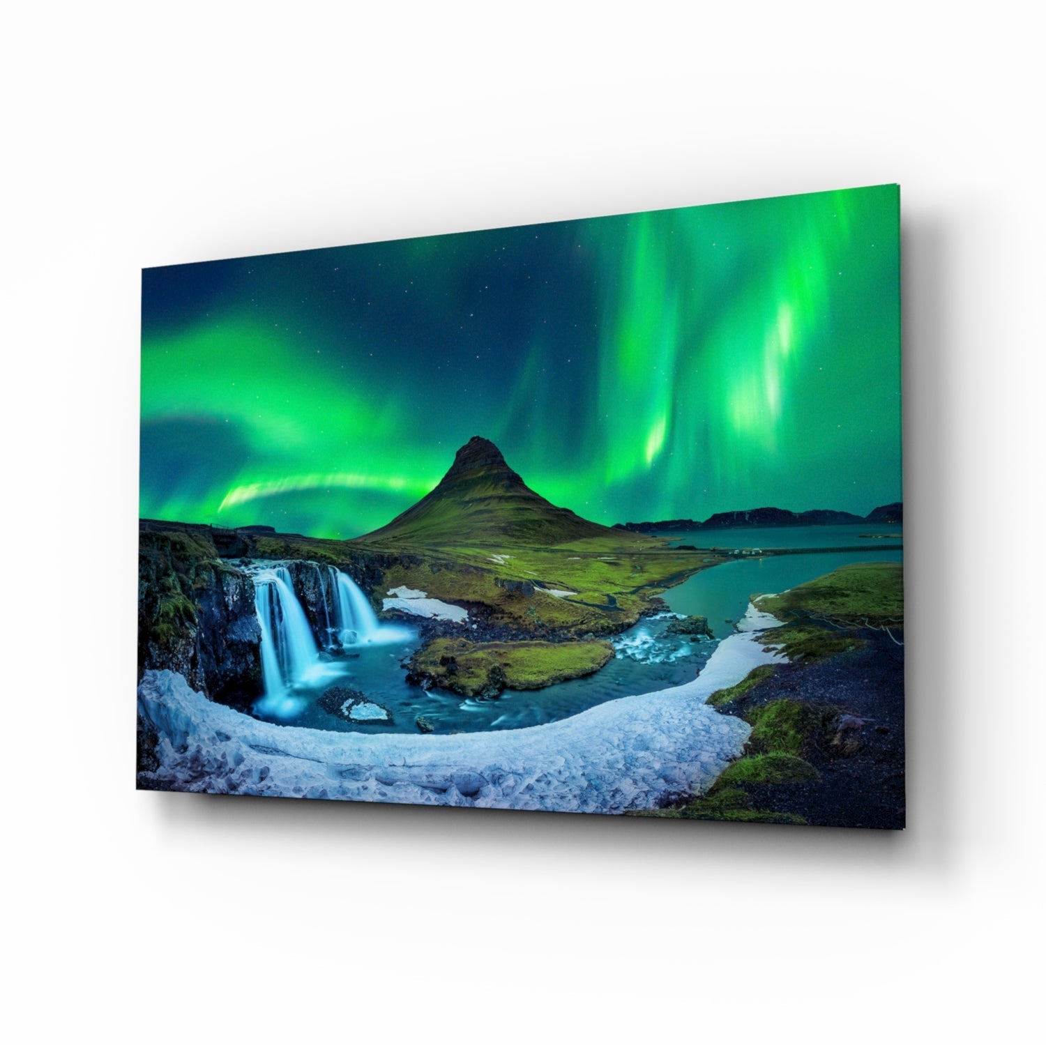 Angled perspective view of glass wall art displaying an Icelandic landscape with green aurora borealis, waterfall, and snow-covered foreground.