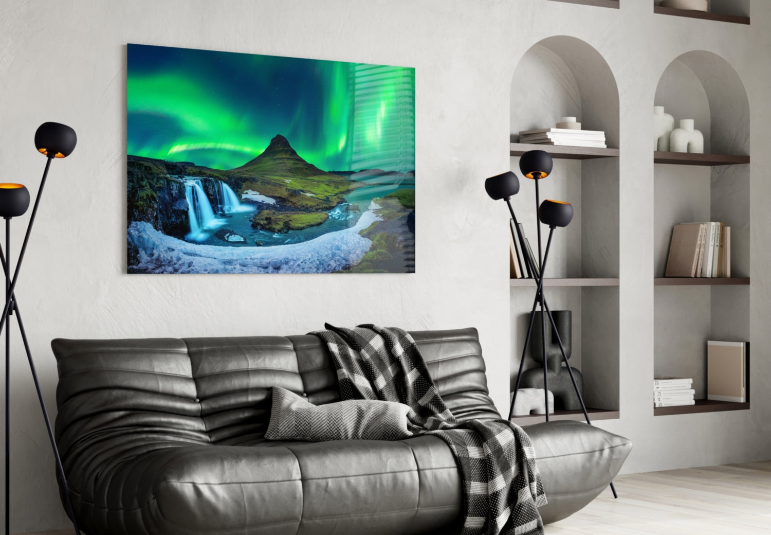 Northern Lights glass wall art displaying green aurora borealis over Icelandic waterfall and mountain landscape, hung above gray leather sofa in modern living room.