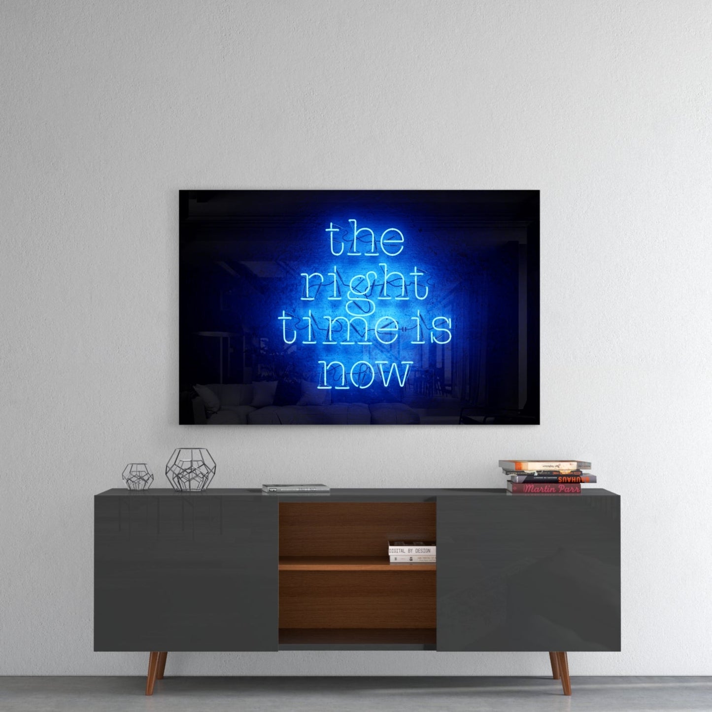 Blue neon glass wall art displaying "the right time is now" mounted above a gray mid-century modern credenza with wooden shelving.