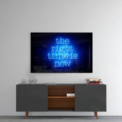 Blue neon glass wall art displaying "the right time is now" mounted above a gray mid-century modern credenza with wooden shelving.