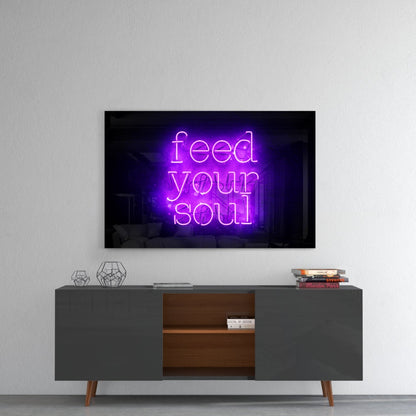 Purple neon "Feed Your Soul" glass wall art mounted above a mid-century modern gray and wood media console in a minimalist interior.