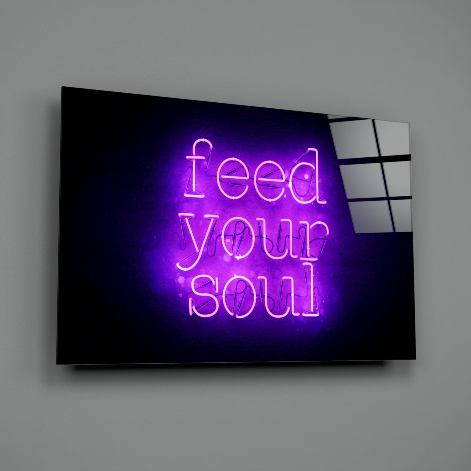 Purple neon "Feed Your Soul" text glowing on black glass panel mounted on gray wall.