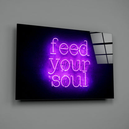 Purple neon "Feed Your Soul" text glowing on black glass panel mounted on gray wall.