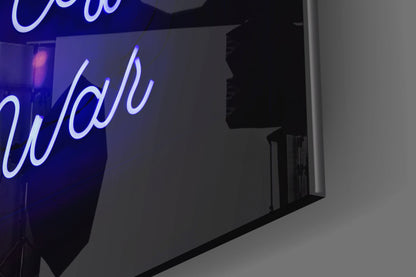Blue neon sign with cursive text mounted on dark glass panel against white wall, angled perspective view.