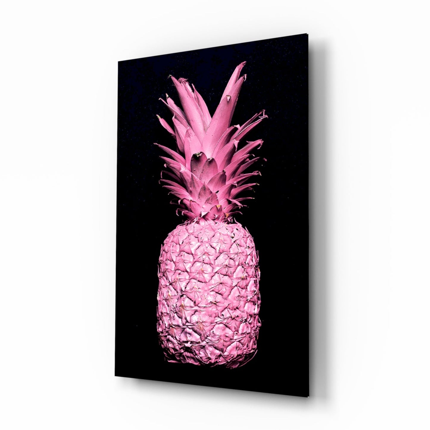 Angled perspective view of a bright pink pineapple with crown leaves against black background on glass panel.