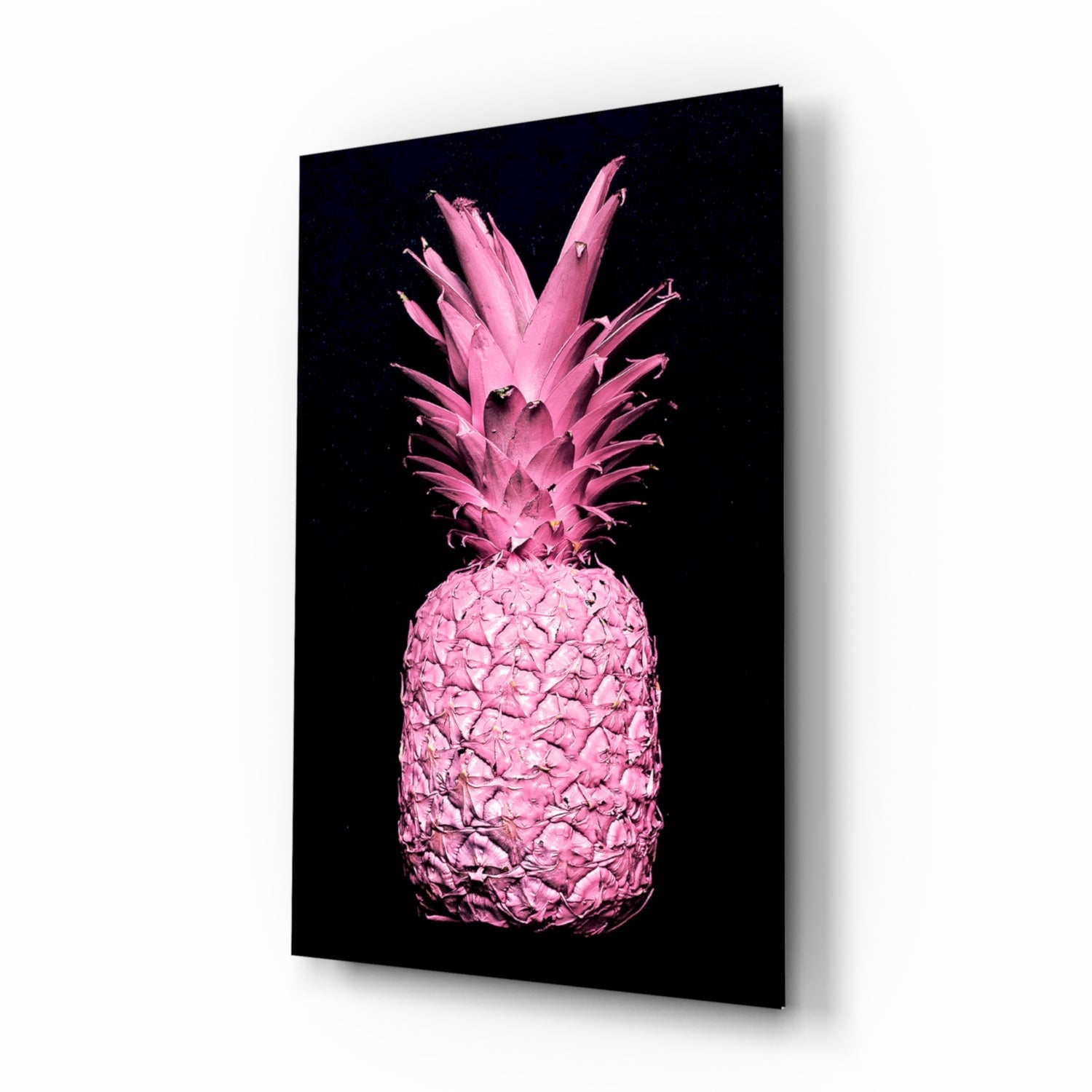 Angled perspective view of a bright pink pineapple with crown leaves against black background on glass panel.