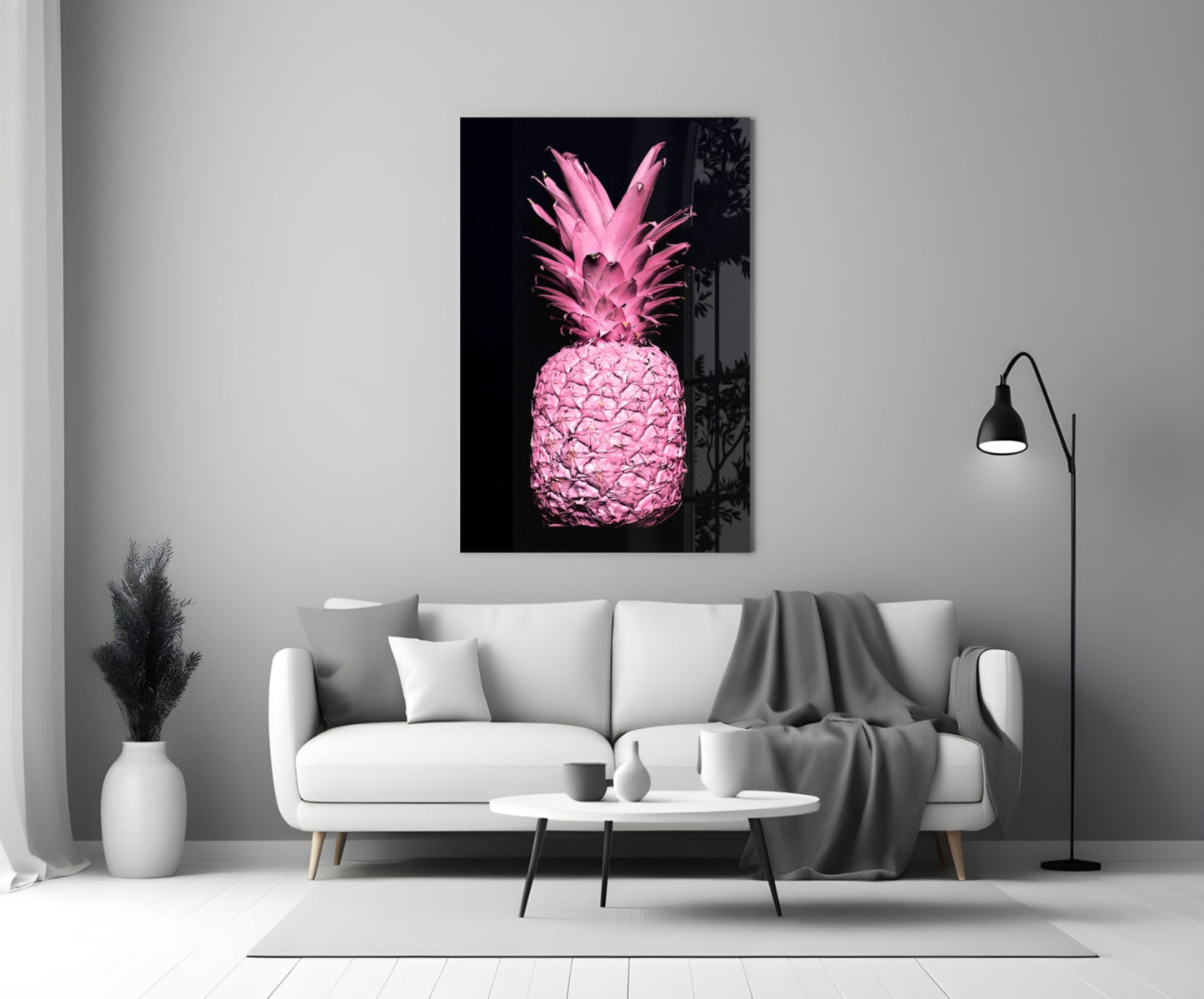 Pink pineapple glass wall art displayed above white sofa in minimalist monochrome living room setting.