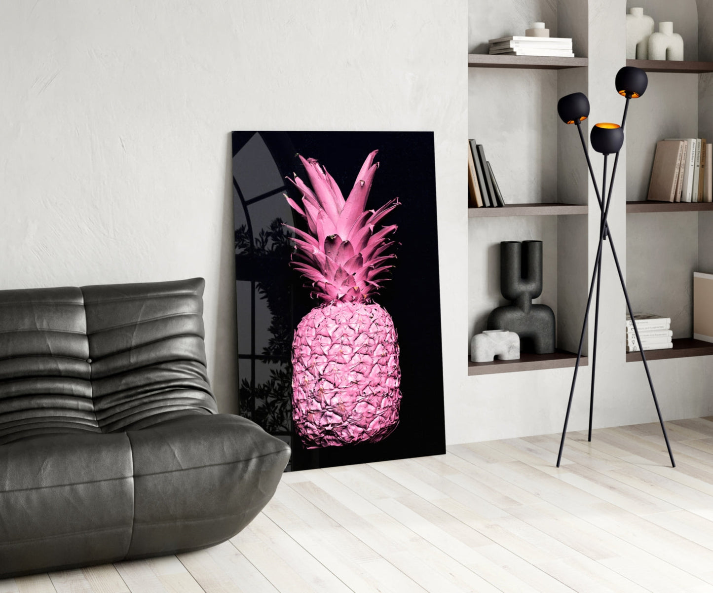 Pink neon pineapple glass art leaning against white wall in modern living room with gray sofa and shelving.