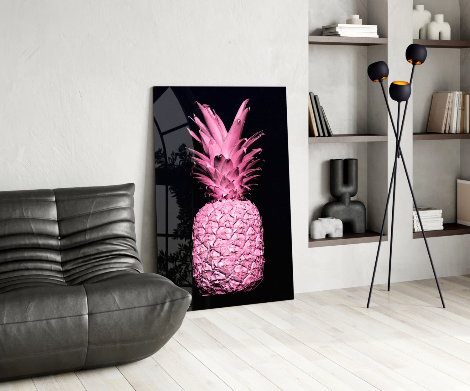 Pink neon pineapple glass art leaning against white wall in modern living room with gray sofa and shelving.