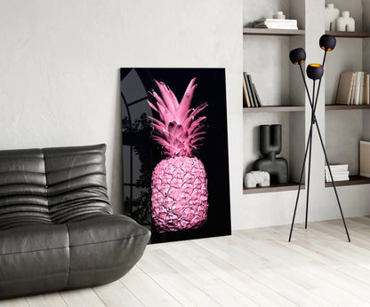 Pink neon pineapple glass art leaning against white wall in modern living room with gray sofa and shelving.