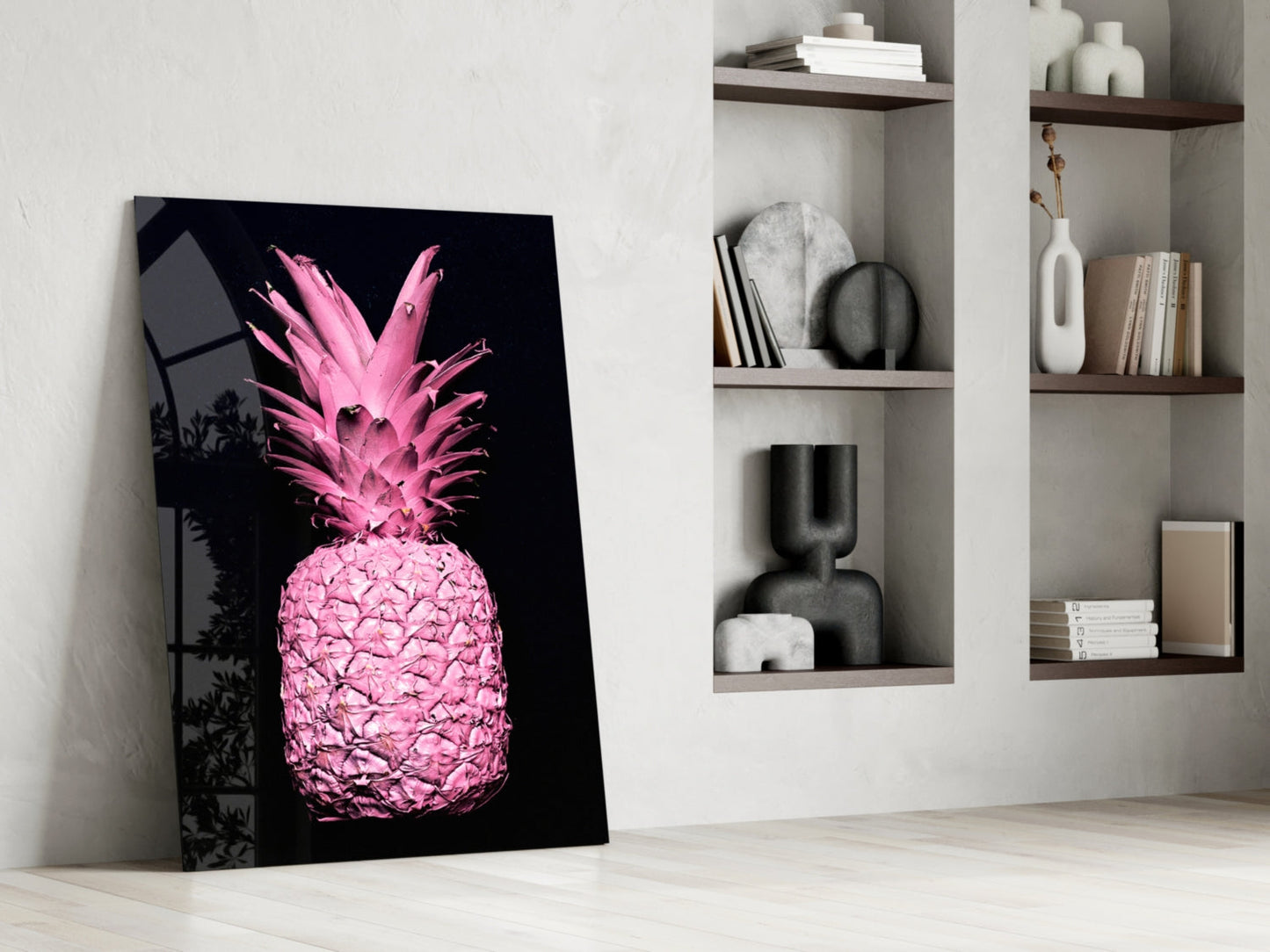 Pink neon pineapple glass art leaning against white wall beside built-in shelving with decorative objects.