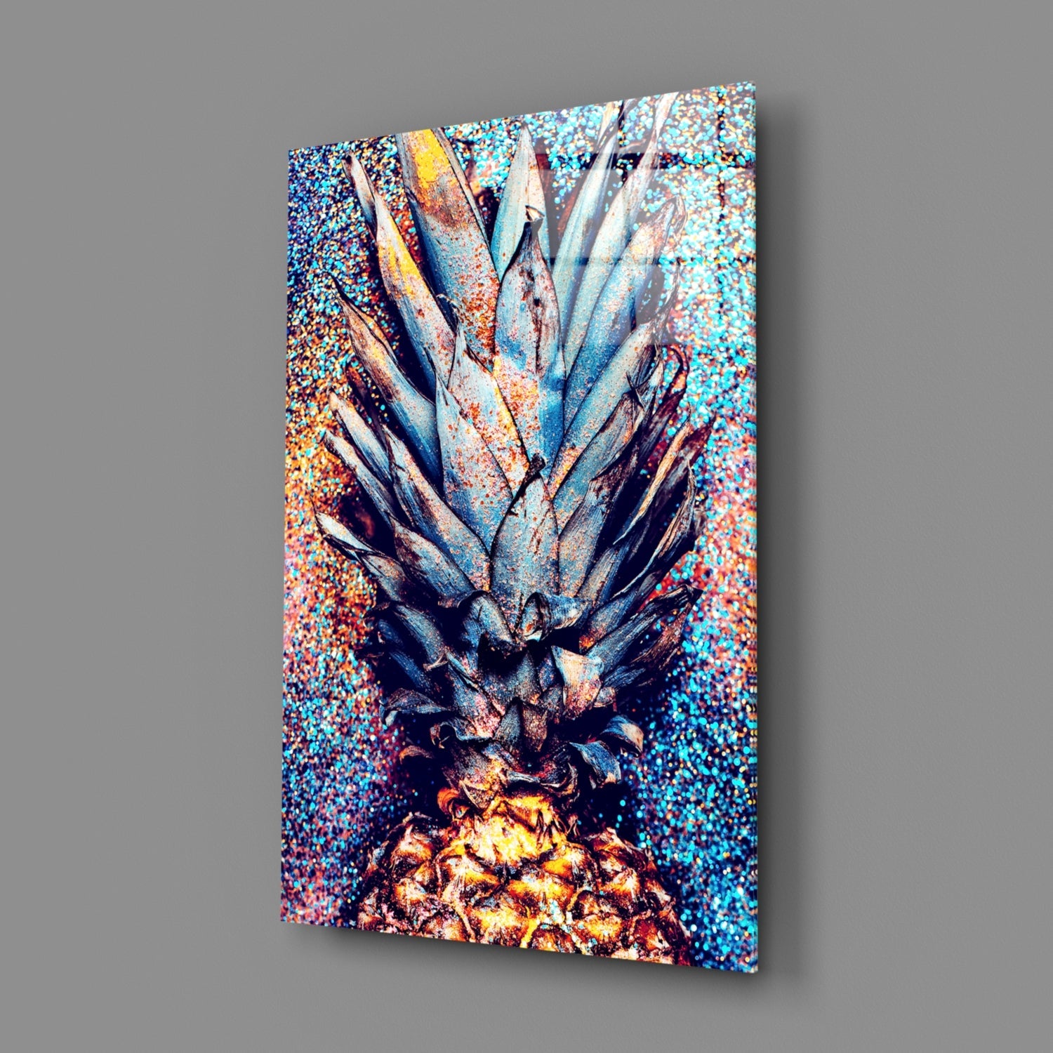 Angled perspective of pineapple glass wall art displaying vibrant turquoise, gold, and deep blue glitter background with metallic fruit detail.