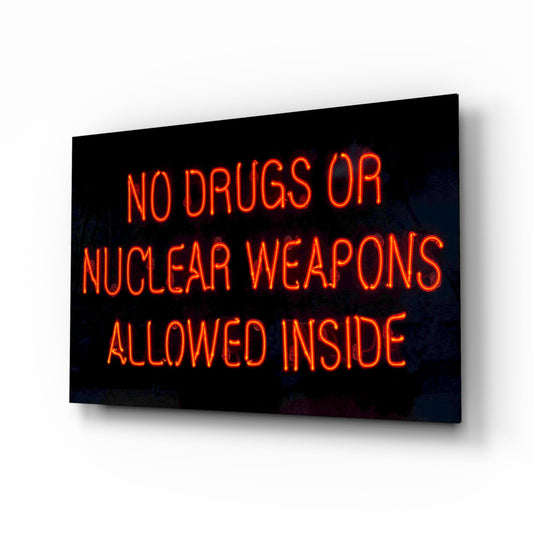Neon glass wall art displaying red glowing text reading "NO DRUGS OR NUCLEAR WEAPONS ALLOWED INSIDE" against black background, angled perspective view.