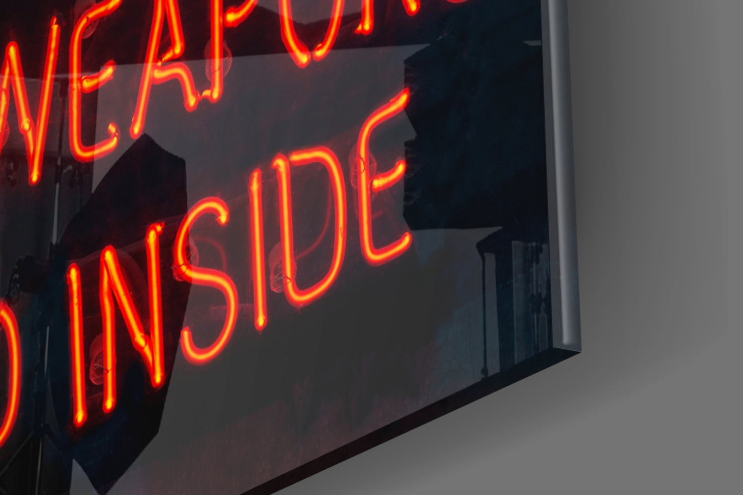 Bright red and orange neon tubing spelling "INSIDE" on dark glass mounted on white wall, photographed at angled perspective.
