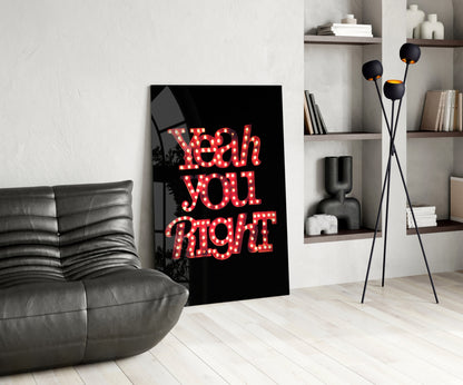 Red neon-style "Yeah you right" glass wall art leaning against wall in modern living room with gray sofa and shelving.