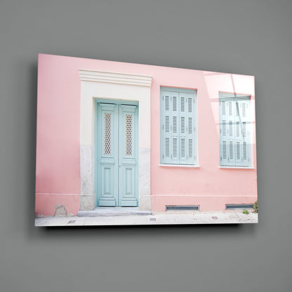 Glass wall art displaying a pink-painted colonial building facade with turquoise double doors and louvered windows.