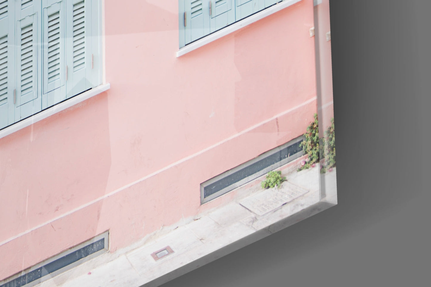 Angled exterior view of pink building facade with white-trimmed windows and dark storefronts at street level.
