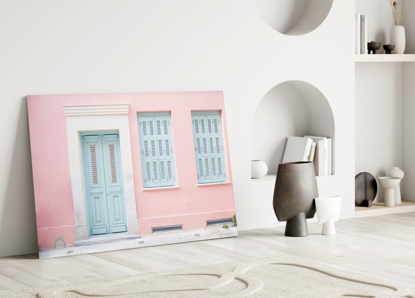 Pink House Glass Wall Art leaning against white wall beside decorative objects and shelving unit.