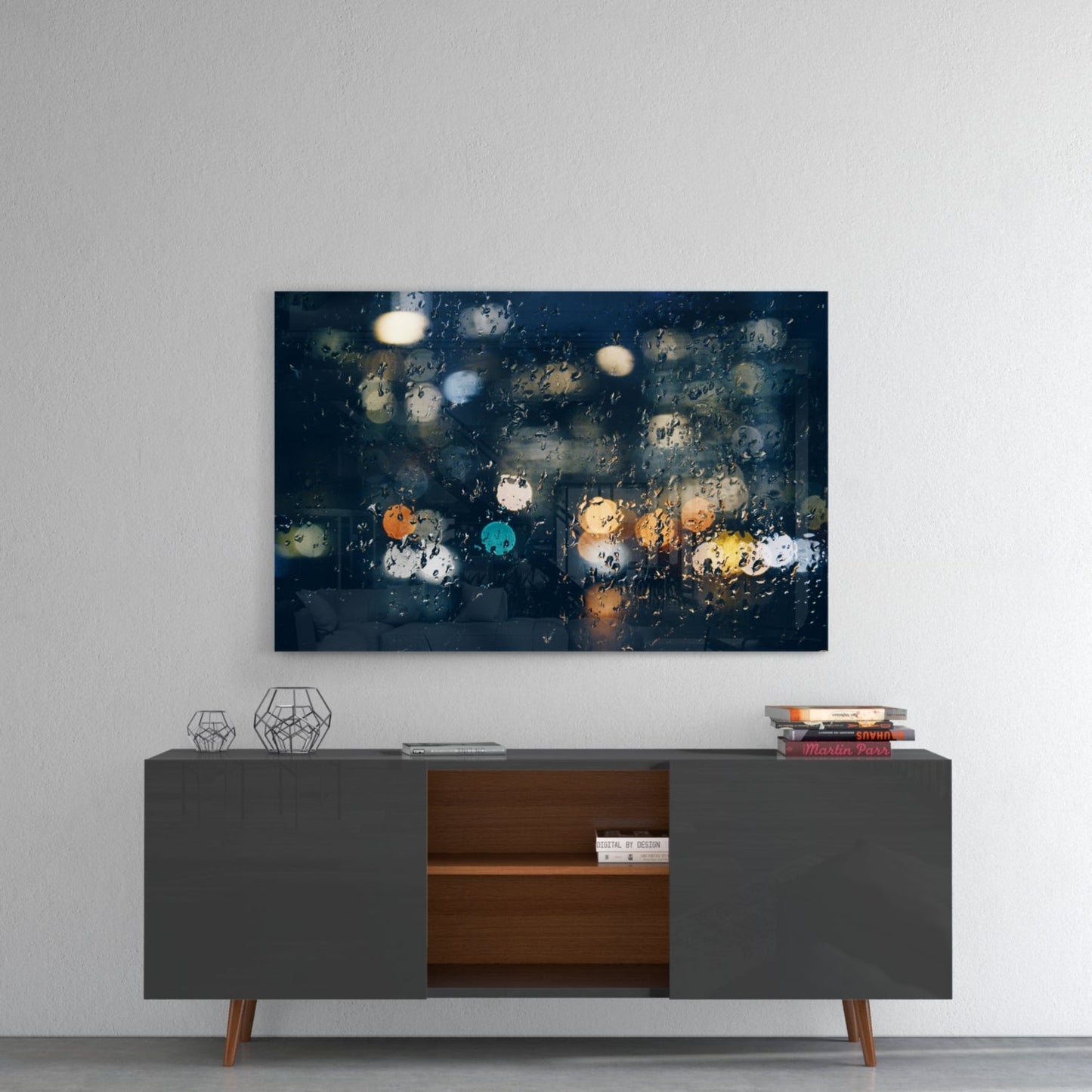 Rain-covered window with blurred city lights in orange, blue, and yellow tones displayed above a mid-century modern console table.