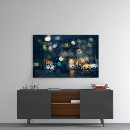 Rain-covered window with blurred city lights in orange, blue, and yellow tones displayed above a mid-century modern console table.