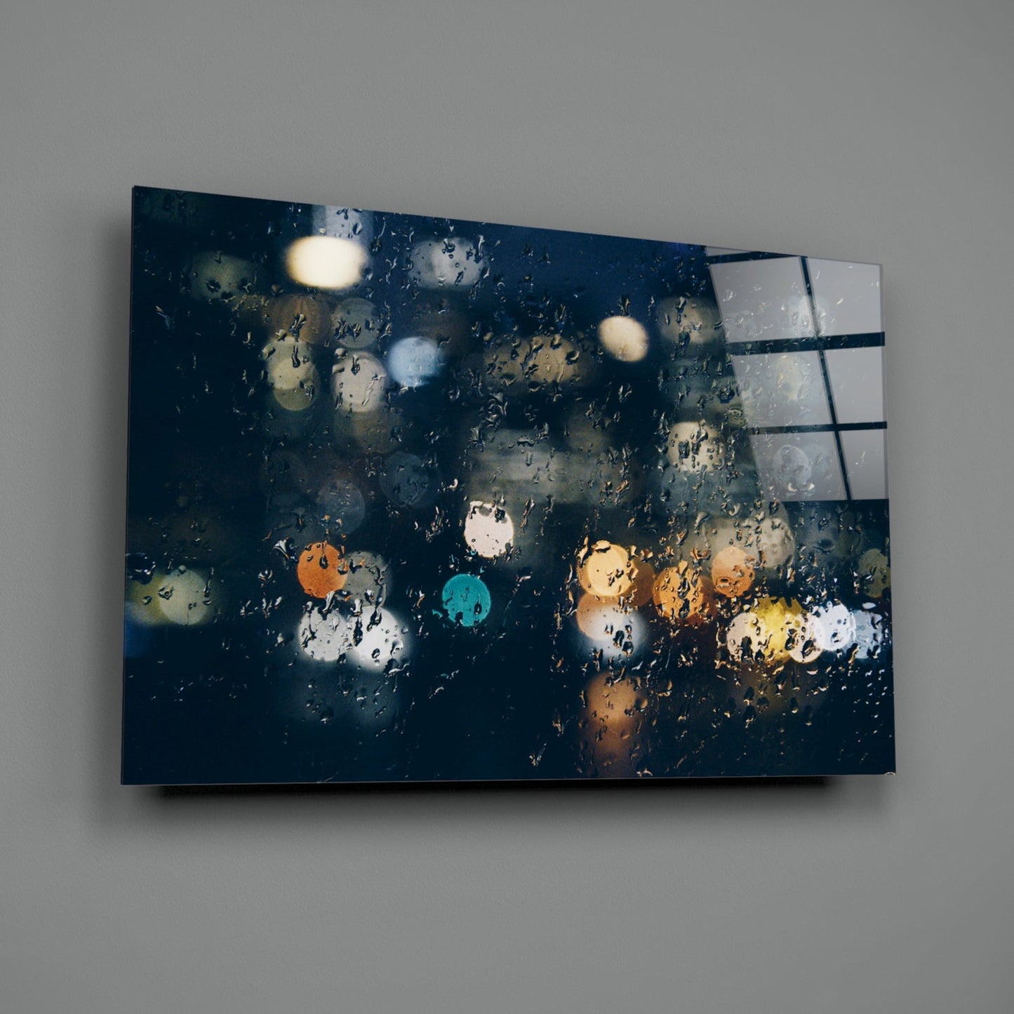 Canvas wall art depicting rain-covered window with colorful bokeh lights and dark blue tones, displayed at angle against gray wall.