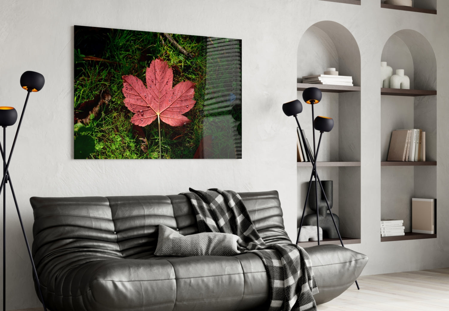 Pink leaf glass wall art displayed above black leather sofa in modern living room with white shelving.