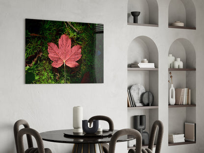 Pink maple leaf glass wall art displayed above a black dining table in a modern white interior with built-in shelving.