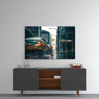 Glass wall art featuring rainy New York City street scene with yellow taxi cabs and pedestrians with umbrellas, displayed above mid-century modern credenza.