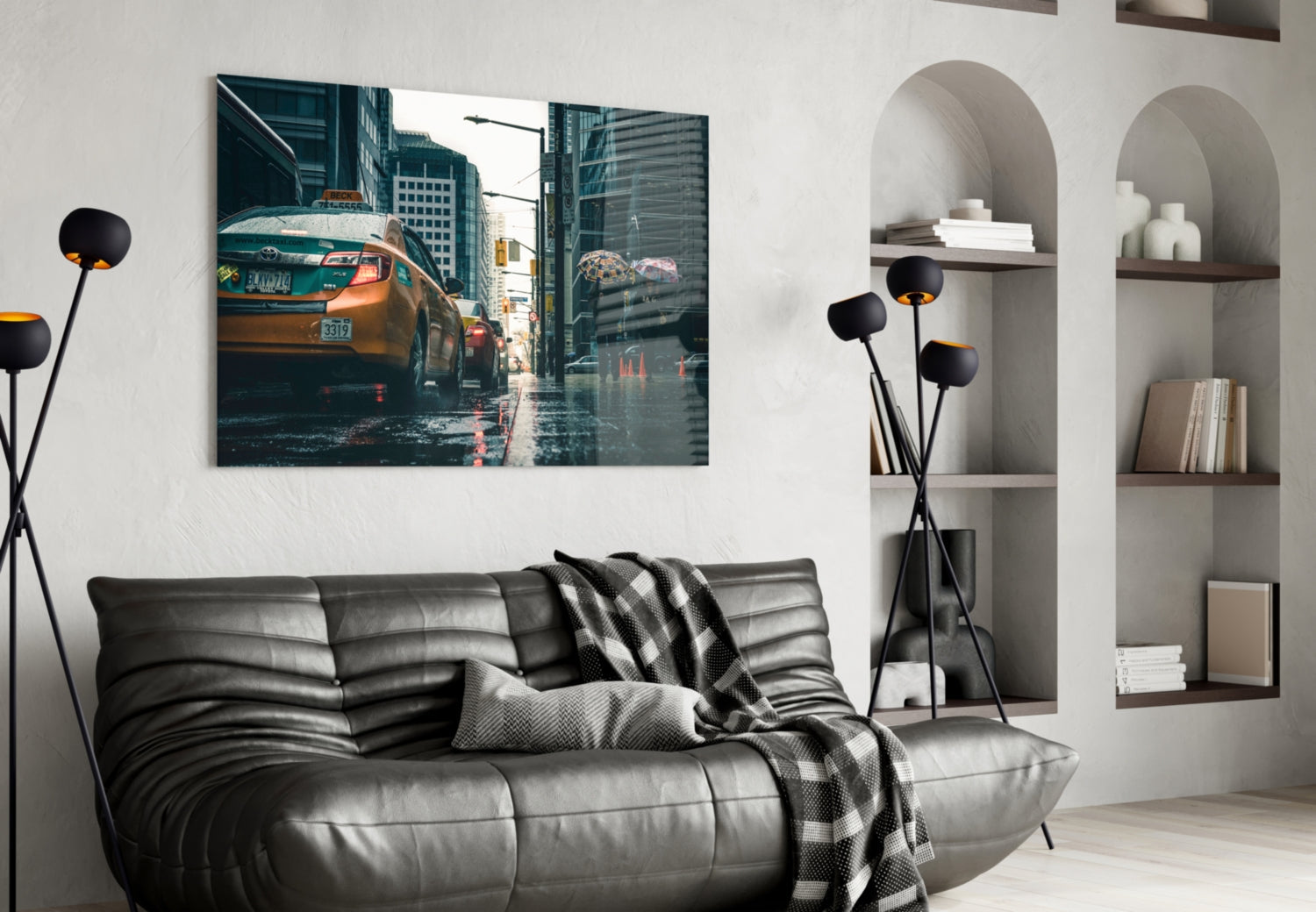 Modern living room with black leather sofa, glass wall art depicting yellow taxi on rainy city street mounted above.