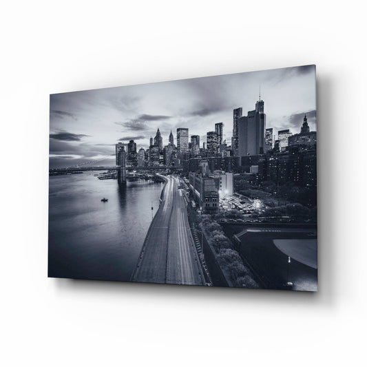 Elevated nighttime view of Manhattan skyline with illuminated skyscrapers, East River, and traffic-lined FDR Drive in monochrome glass wall art.