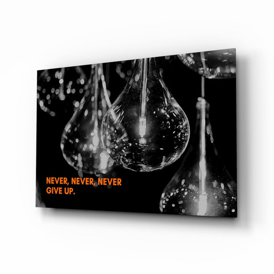 Black and white glass wall art featuring water droplets suspended in teardrop shapes with orange text reading "NEVER, NEVER, NEVER GIVE UP" against dark background.