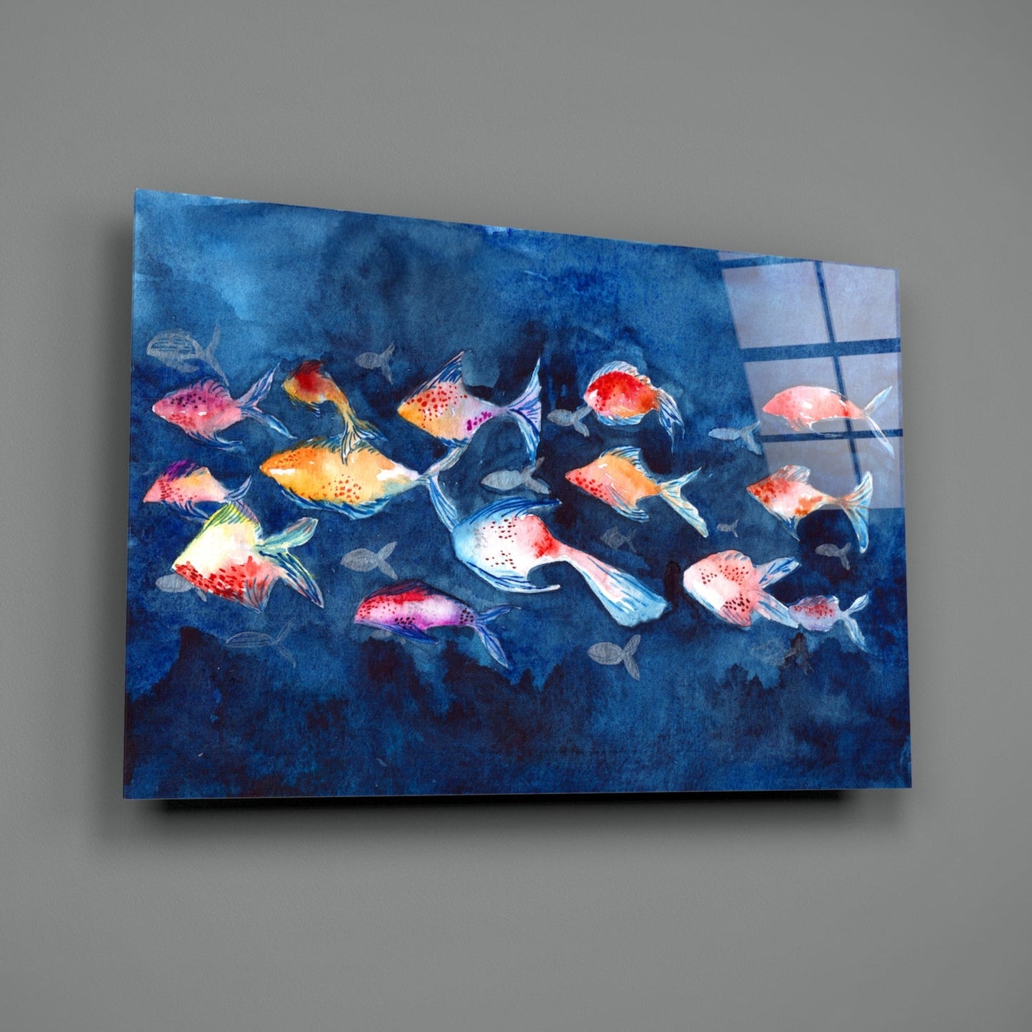 Colorful illustration of red, orange, and yellow fish swimming in deep blue water on a glass wall art panel displayed at an angle.