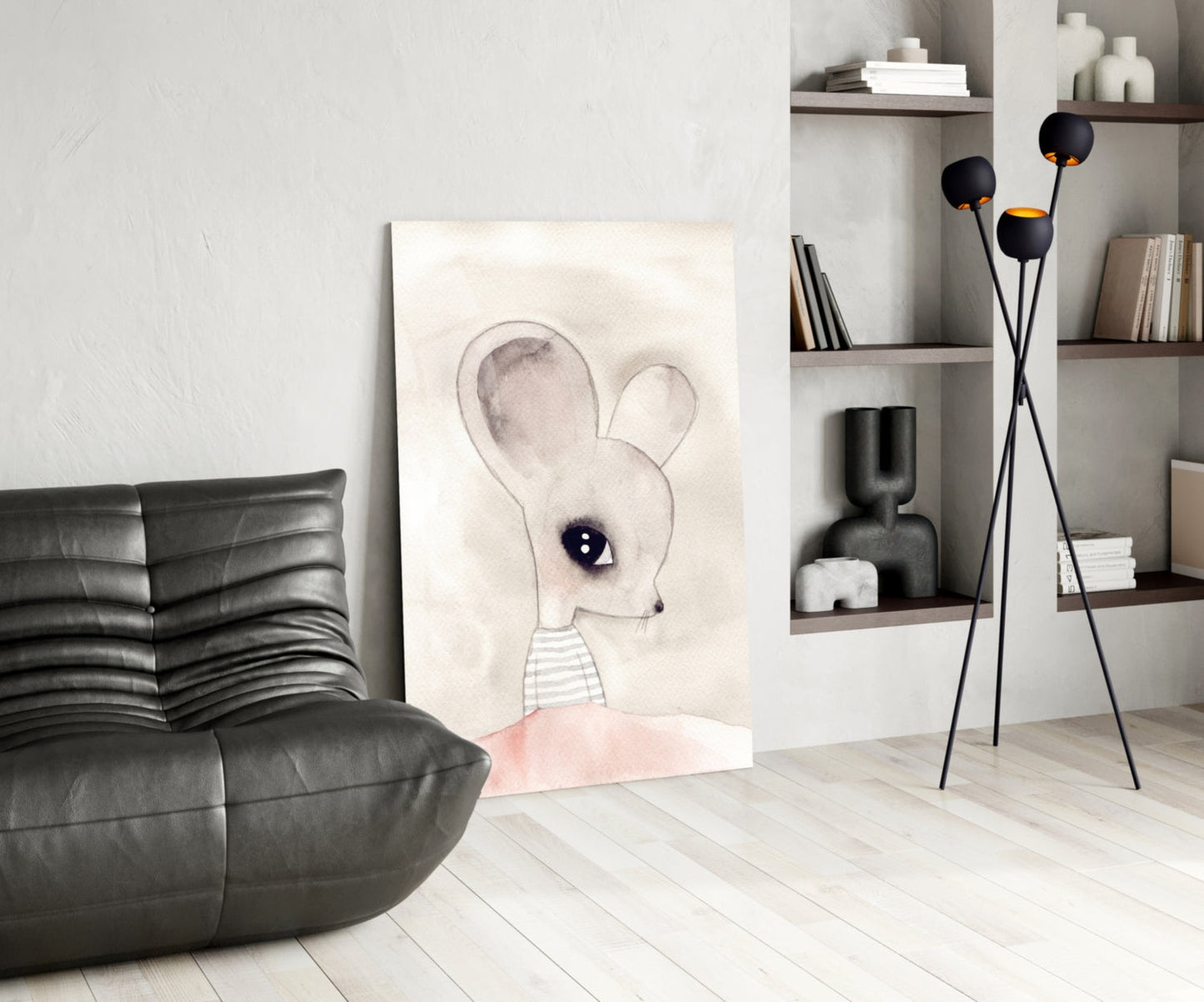 Cute mouse glass wall art displayed on floor against white wall in modern living room with black leather chair and shelving unit.